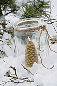 Windlicht mit Honigkerze in Tannenbaumform und Schnee