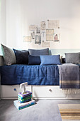 Collage of pictures above bed with various blue scatter cushions