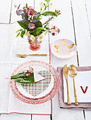 Beschriftetes Blatt als Namensschild auf rosafarben gedecktem Tisch
