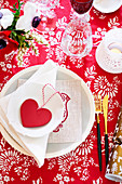 Festive place setting with heart decoration on a red and white tablecloth