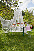 Set garden table and two chairs under mosquito net in garden
