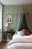 Vintage-style bedroom with canopy over bed and green wallpaper