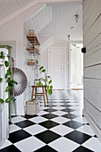 Bright hallway with white wood-panelled walls and chequered floor