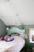 Bed with canopy, grey walls and sloping ceiling in girl's bedroom
