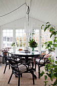 Runder Tisch mit Stühlen und Zimmerpflanzen im Wintergarten