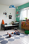Toys on rug in boy's bedroom with green wall
