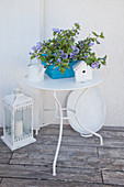 Blue-flowering plants in basket on metal table and white ornaments