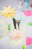 Cutlery pouch decorated with paper flowers on table