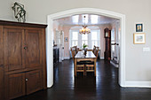 Corner cupboard next to open doorway leading to wooden table in dining room
