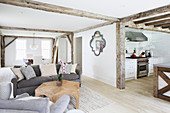 Offener Wohnraum mit rustikalen Holzbalken und Blick in die Küche