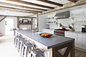 Metal stools at island counter in open-plan country-house kitchen