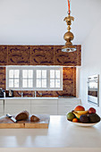 Fruit bowl in modern kitchen with gold-patterned tiles