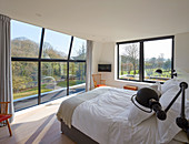 Floor-to-ceiling glass wall in bedroom overlooking garden