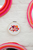 Handcrafted accessories: embroidery frames. mottoes and crocheted mirror frames on white brick wall