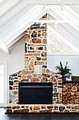 Firewood stacked next to fireplace with stone surround and chimney breast