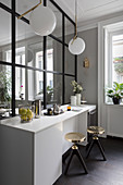 Gilt stools at kitchen counter against glass and steel partition wall