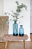Two blue vases and eucalyptus branches on stool