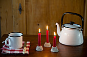 Drei rote, brennende Kerzen in Kerzenhaltern in Kuchenform