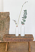 Zwei weiße Vasen mit Eukalyptuszweig auf einem Schemel
