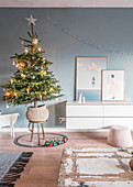 Christmas tree next to sideboard in living room with blue wall
