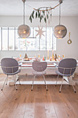 Spherical silver lamps above festively set dining table and grey chairs