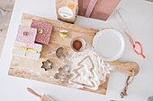 Christmas presents and baking utensils on wooden board seen from above