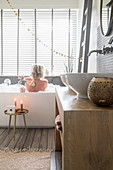 Twin countertop sinks on washstand in bathroom with Christmas decorations and woman in bathtub