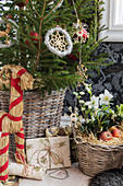 Christmas tree decorated with straw figurines, basket of hellebores and gifts