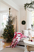 Polstersofa mit roter Decke neben Weihnachtsbaum im Wohnzimmer