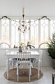 Weißer Tisch mit Stühlen in weihnachtlichem Wintergarten