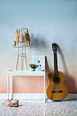 Guitar and table on the wall with gradient in pink and blue