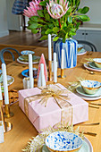 Rosafarbenes Geschenk, Kerzen und Blumen auf gedecktem Tisch