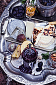 Various cheeses, jam and fruit on vintage silver tray