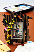 Photo of children in unusual frame decorated with sprig of flowers