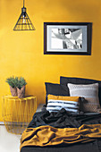Bed and metal bedside table against yellow wall