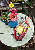 Gardening tools and jug of flowers on garden table