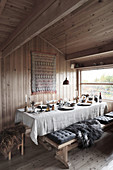 cushions and fur blanket on bench next to dining table set with linen cloth in chalet dining area