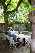 Laid table with vintage seating under trees