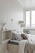 Double bed, shelves and pendant lamps in bright bedroom