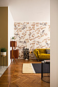 Mustard-yellow sofa against patterned wallpaper and 50s cabinet in living room