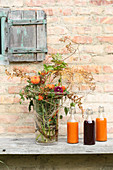 Autumnal bouquet and three bottles of juice against outside wall of house