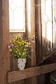 Jug of wildflowers on wooden beam