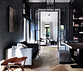 Desk, shelf and sofa in elegant study with dark walls