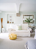 Golden pouffe in front of sofa in white living room