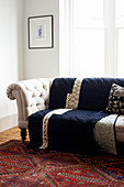 Dark blue quilt on pale button-tufted sofa