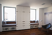 White, floor-to-ceiling wardrobe flanked by window seats fitted in window niches