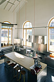 Island counter with barstools in converted loft with arched windows