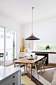 Pendant lamp above dining table with chairs in open living room