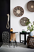 Various side tables against black and white wall with bowls