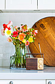 Bouquet of colored silk poppies in a glass vase, in front of retro radio